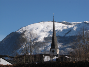 Kirchturmspitze und schneebedeckte Berge